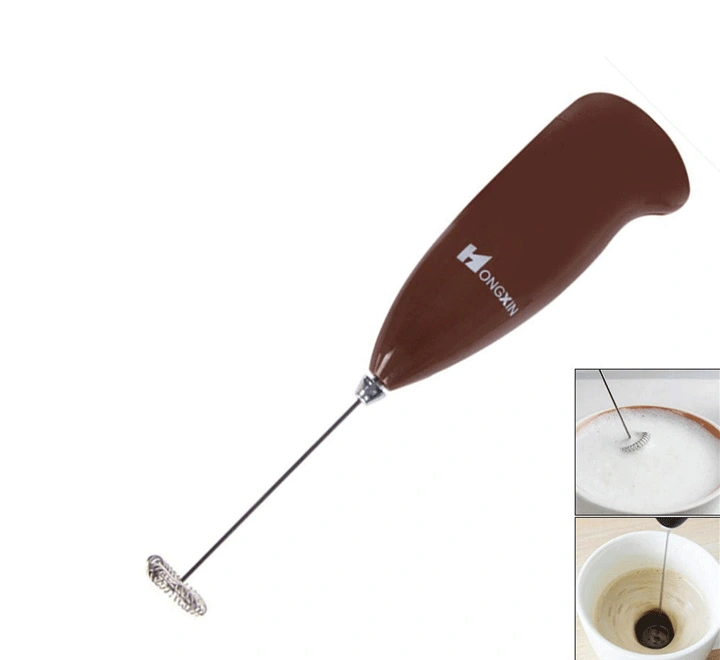 Brown handheld electric milk frother with stainless steel whisk end whipping milk foam and mixing coffee in a mug