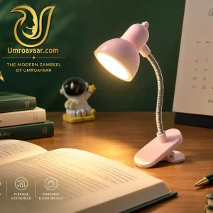 Pink mini clip-on LED desk reading lamp with flexible metal gooseneck illuminating an open book on a study table