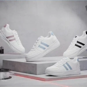 White low-top sneakers in pink, light blue, and black side stripe variations displayed on grey podiums in a studio setting.